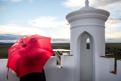 Woman with red umbrella against sky