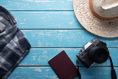 High angle view of camera with hat by passport and clothing on table