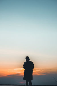 Rear view of silhouette man standing against sky during sunset