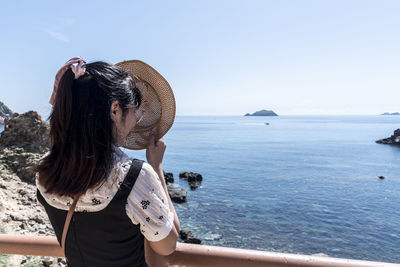 Rear view of woman looking at sea against clear sky