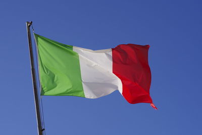 Low angle view of flag against clear blue sky