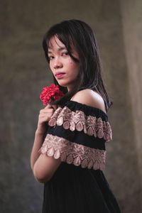 Close-up of woman holding rose standing against blurred background