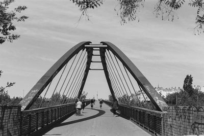 People on footbridge against sky