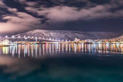 Scenic view of illuminated bay against sky at night