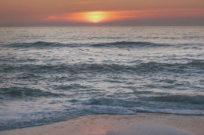 Scenic view of sea against dramatic sky during sunset