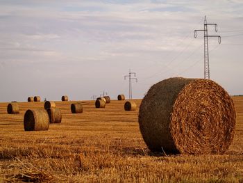 Hay bales on field against sky