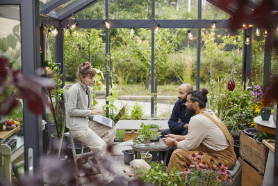 Smiling friends talking in greenhouse