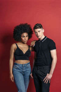 Stylish diverse girlfriend and boyfriend posing in a studio shooting with red background