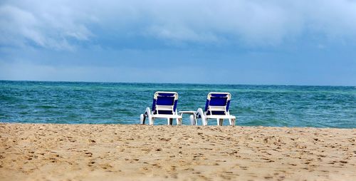 Chairs on beach against sky