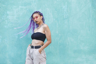 Portrait of woman with dyed hair standing against wall
