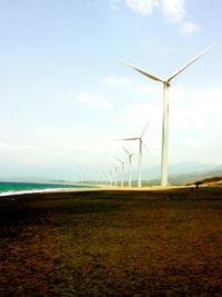 Windmills on field against sky