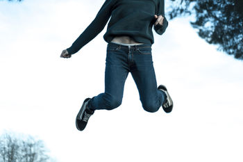 Low section of man jumping on snow