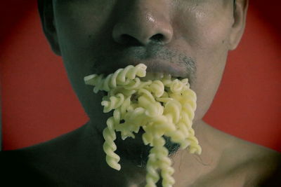 Close-up of man with pasta against red background