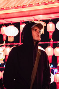 Close-up of young man against lanterns at night