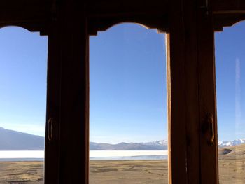 Scenic view of sea against clear blue sky seen through window