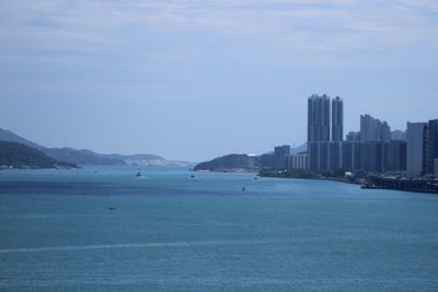 Sea by city buildings against sky