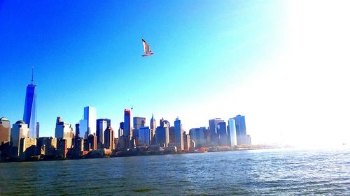 Airplane flying over sea against clear blue sky