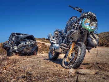 Damaged motorbike and car against blue sky