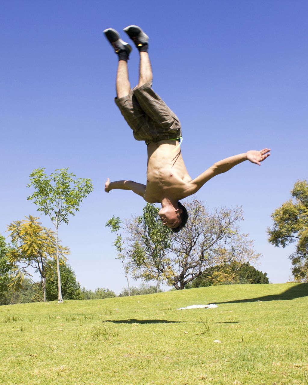 mid-air, full length, jumping, lifestyles, leisure activity, clear sky, arms outstretched, fun, freedom, enjoyment, grass, arms raised, blue, casual clothing, vitality, skill, low angle view, carefree