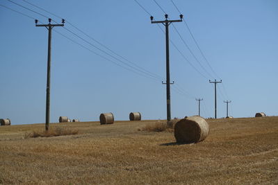 Hay bales on field against clear sky