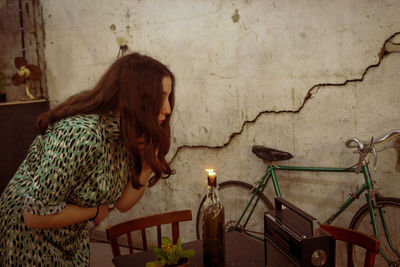 Woman sitting on table against wall