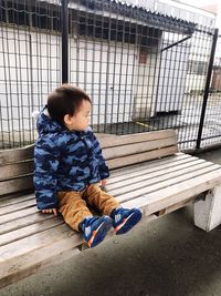 Cute boy looking away while sitting outdoors