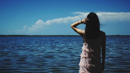 Woman standing in sea against sky