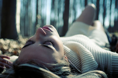 Carefree young woman lying in forest