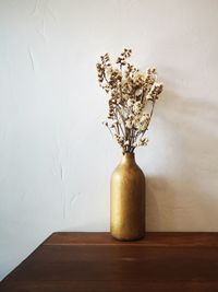 Close-up of white flower vase on table against wall at home