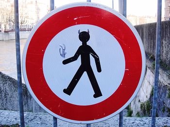 Close-up of drawing on road sign against metallic fence
