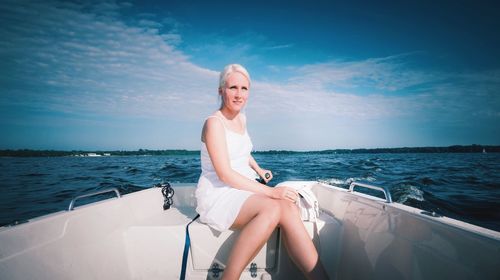 Woman sitting on boat sailing in sea against sky