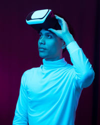 Portrait of young man standing against blue background