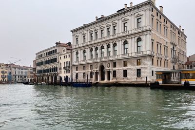 Buildings by river against sky