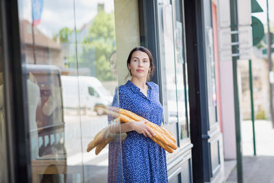 Young woman buying a french baguette