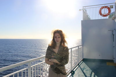 Woman standing by railing on boat over sea