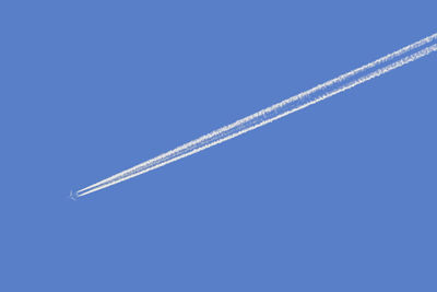 Low angle view of airplane flying against clear blue sky