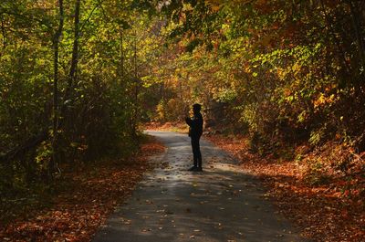 Man standing amidst trees in forest during autumn