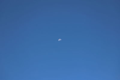 Low angle view of moon against clear blue sky