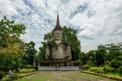 Old buddha statue at sala keoku against cloudy sky