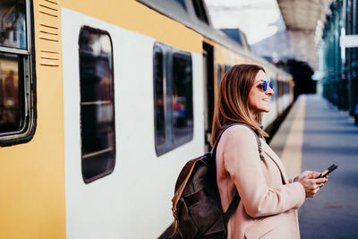 Full length of woman standing by train at railroad station