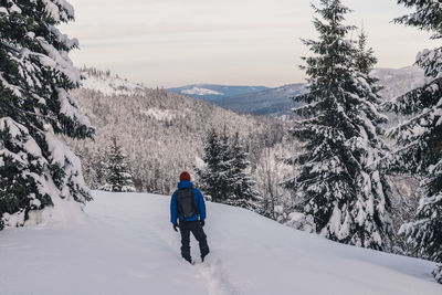 Rear view of man walking on snow covered mountain