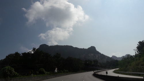 Road by trees against sky