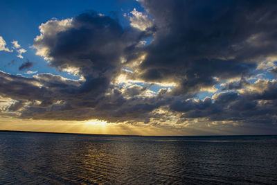 Scenic view of sea against dramatic sky during sunset