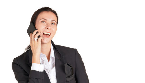 Smiling young woman using smart phone against white background