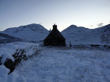 Built structure on snow covered mountain against sky