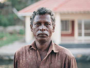 Portrait of man standing against house