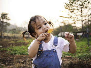 Girl eating flavored ice while standing on land