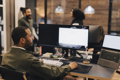 Rear view of businessman using computer at desk in office