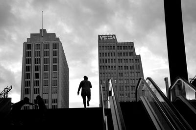 Low angle view of mature man moving up on steps against sky