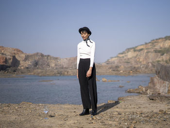 Full length of woman standing by lake against sky